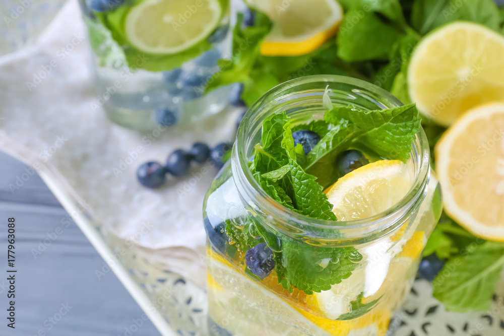 Tray with glassware of infused fruit water on wooden table, closeup Tray with glassware of infused fruit water on wooden table, closeup