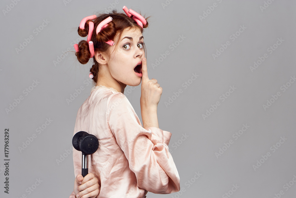 a woman with curlers is hiding something behind her back Stock Photo