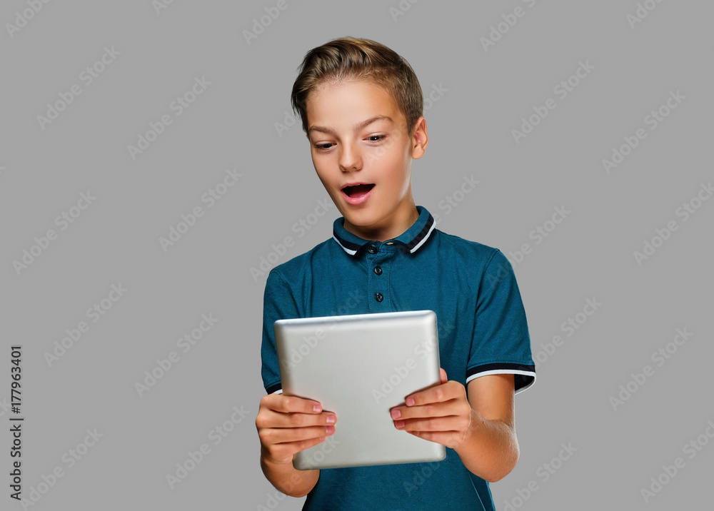 The positive teenager boy holds tablet PC. The positive teenager boy holds tablet PC.