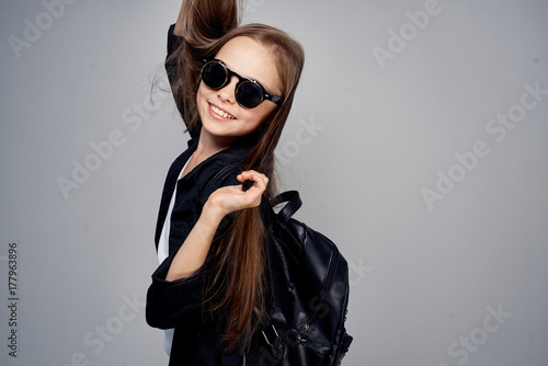 little girl with long hair wearing glasses and with backpack smiling