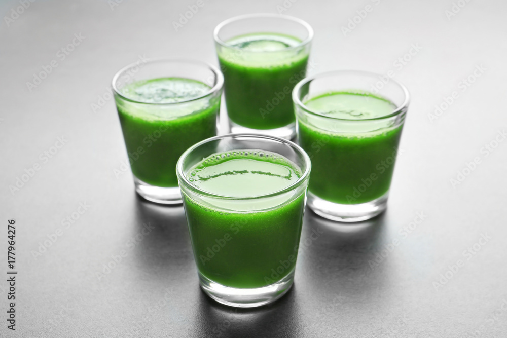 Shots of healthy wheat grass juice on grey background Shots of healthy wheat grass juice on grey background