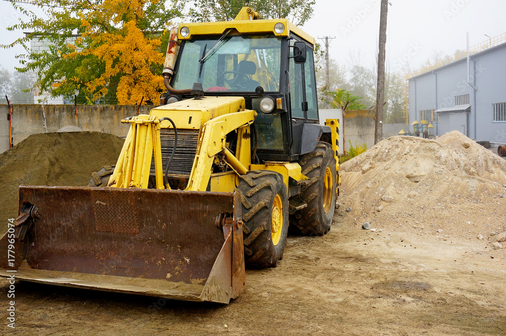 The concept of agronomy, a yellow tractor with a bucket demonstrates work The concept of agronomy, a yellow tractor with a bucket demonstrates work