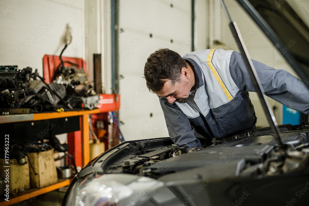 Car mechanic man at the garage fixing the engine. Car mechanic man at the garage fixing the engine.
