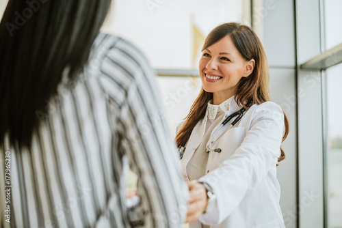 Female doctor talking and touching woman patient for encouragement. photo