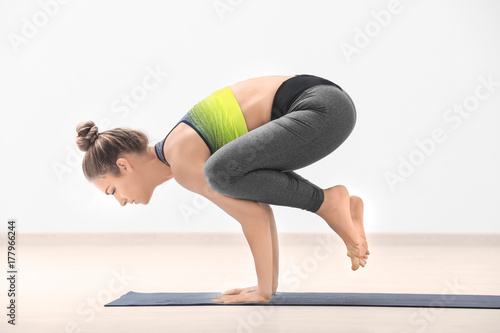 Beautiful young woman practicing yoga indoors