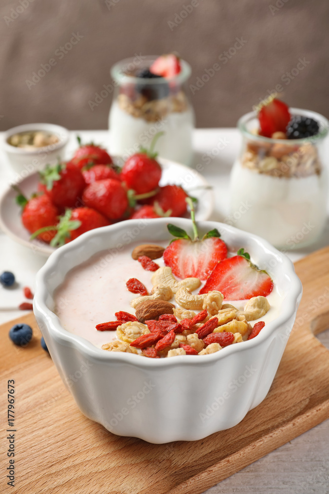 Tasty breakfast with goji berries in dish on wooden board Tasty breakfast with goji berries in dish on wooden board