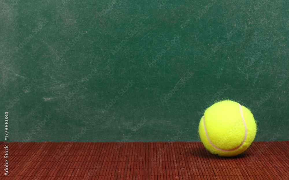 Tennis ball on desk, chalkboard background