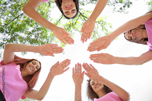 Slika na platnu Young women in pink t-shirts joined in circle outdoors