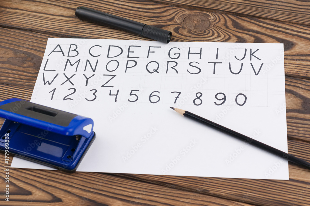 Handwritten capital letters and digits on white sheet and black felt