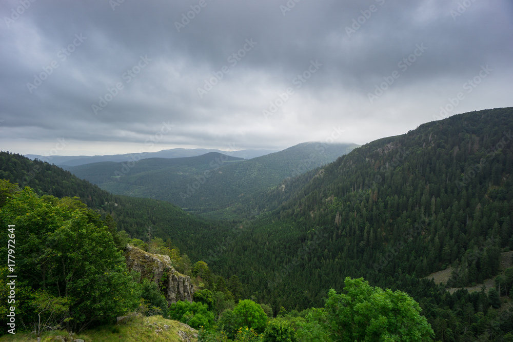 France - Rocky valley in forest and wooded landscape with rain clouds