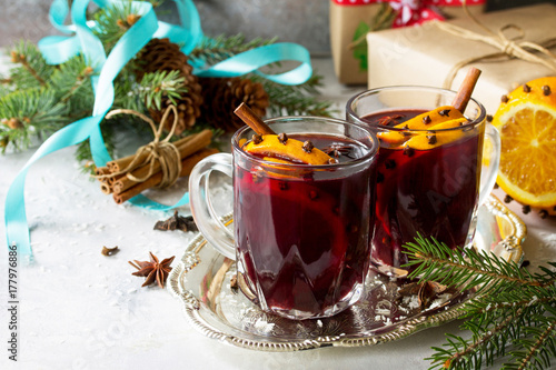Homemade Christmas cocktail mulled wine red wine with cinnamon sticks, oranges and cloves, served in two cups on a gray stone or slate. Copy space.
