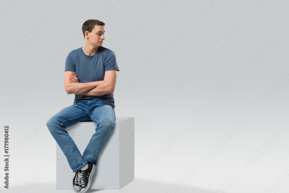 Man sitting on a cube and looking away - isolated - obrazy, fototapety, plakaty 