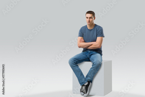 young man sitting on white cube. isolated