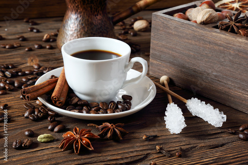 Black coffee in a white cup and various spices