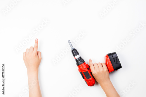 Child's hands on white background. Boy pointing finger up and holding toy drill.