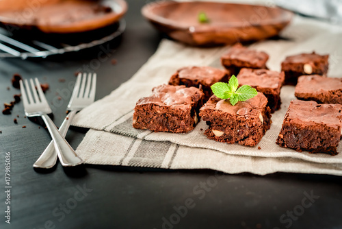 homemade exquisite chocolate brown cake decorated with mint on a kitchen towel on a dark wooden table