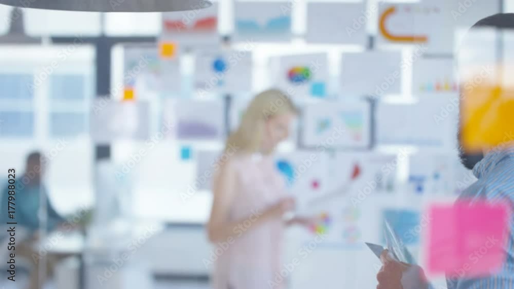 Creative business people looking at photos & printed graphs in a meeting Creative business people looking at photos & printed graphs in a meeting