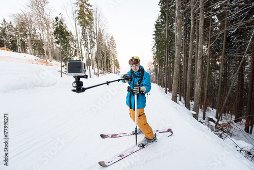 Skier man taking selfie with stick over forest on the winter resort Bukovel