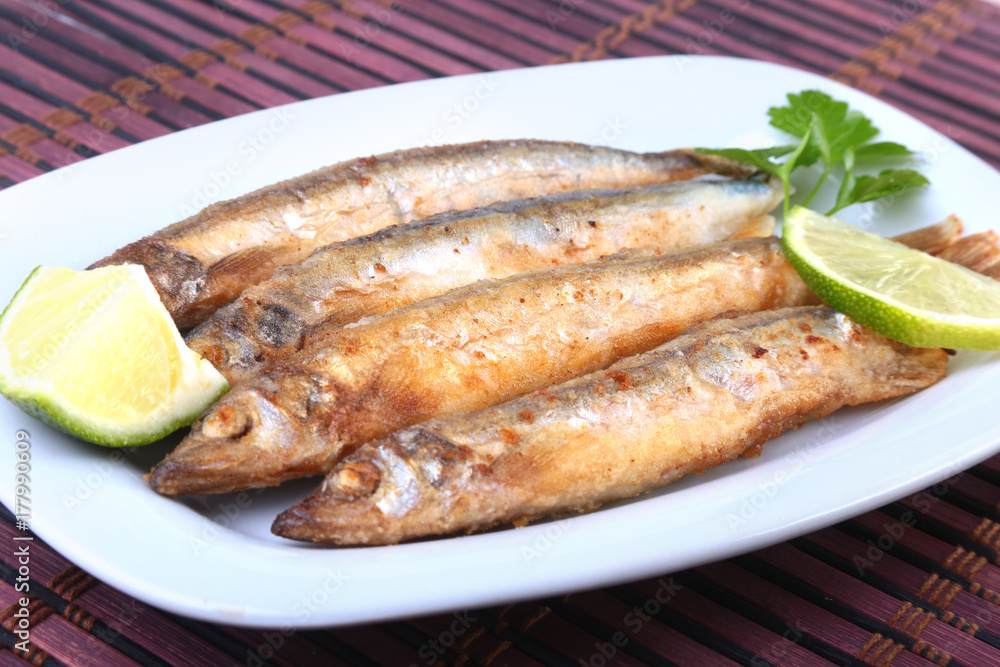 Deep frying small fish capelin and sliced lemon on white plate. Good snack to beer. Deep frying small fish capelin and sliced lemon on white plate. Good snack to beer.