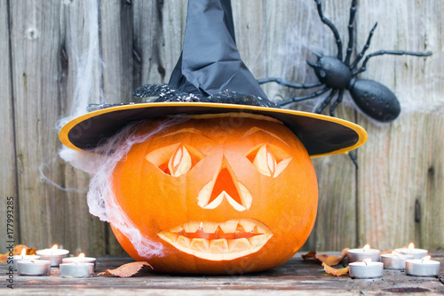 Gruseliger Halloween Kürbis mit Spinnweben und Spinne vor Holzhintergrund