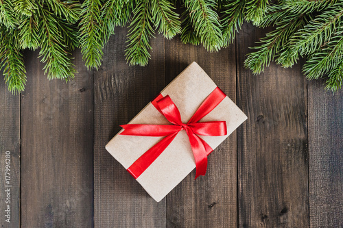 Christmas fir tree branches and gift box on dark rustic wooden background with copy space for text