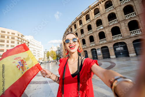 Foto Portrait of young woman tourist in red dress standing with spanish flag in front