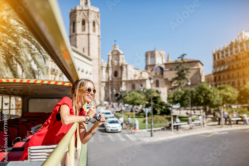 Tablou canvas Young happy woman tourist in red dress having excursion in the open touristic bu