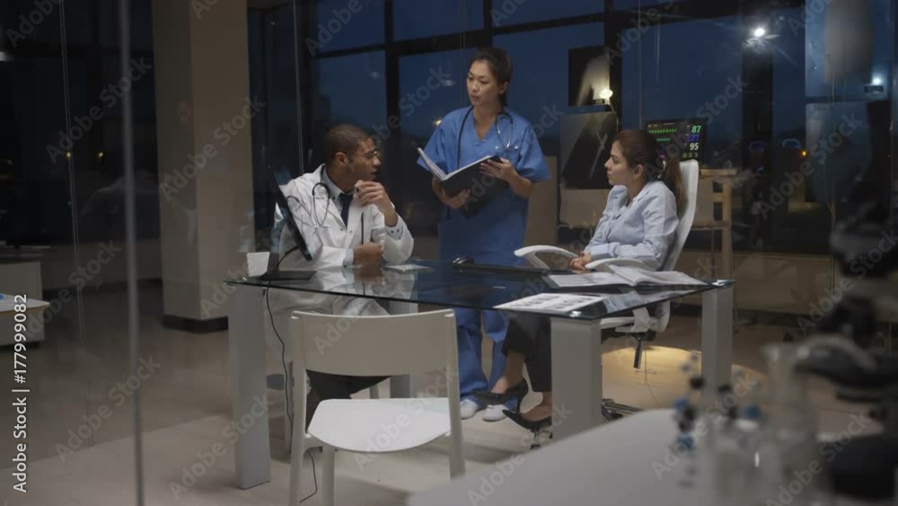 Medical team on night shift having a meeting, looking at patient scans Medical team on night shift having a meeting, looking at patient scans
