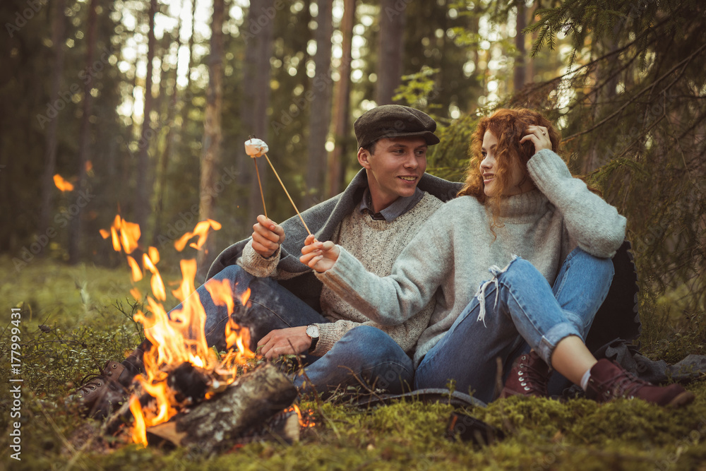 Love story. Couple in forest cooking marshmallows