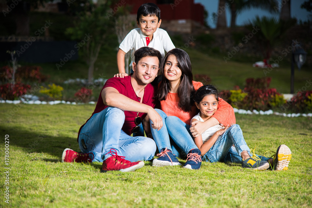 Indian family sitting in lawn - happy and young indian couple with two ...