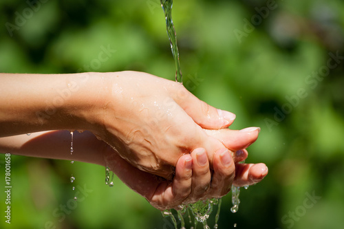 Young Woman washing hand outdoors. Natural drinking water in the palm. Young hands with water splash, selective focus