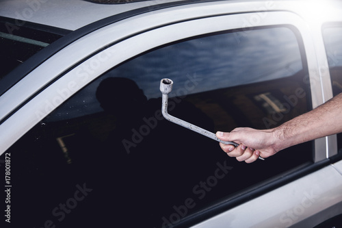 Принти на полотні Auto thief in black balaclava trying to break into car with crowbar