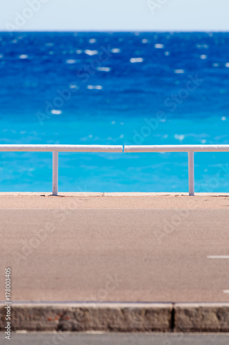 Footpath and railings in front of a bright blue sea