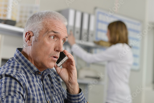 Man in office on cellphone, surprised expression