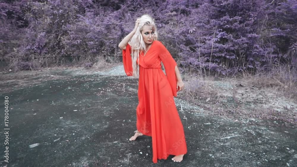 Mysterious woman in red dress with gunshot wound in her head standing, walking in the forest - time freeze slow motion concept Mysterious woman in red dress with gunshot wound in her head standing, walking in the forest - time freeze slow motion concept