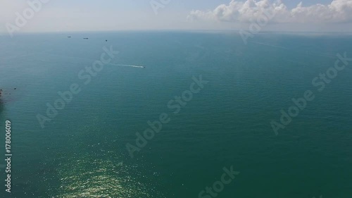 Sunrays reflecting in calm turquoise sea with boats afar, beautiful seascape photo