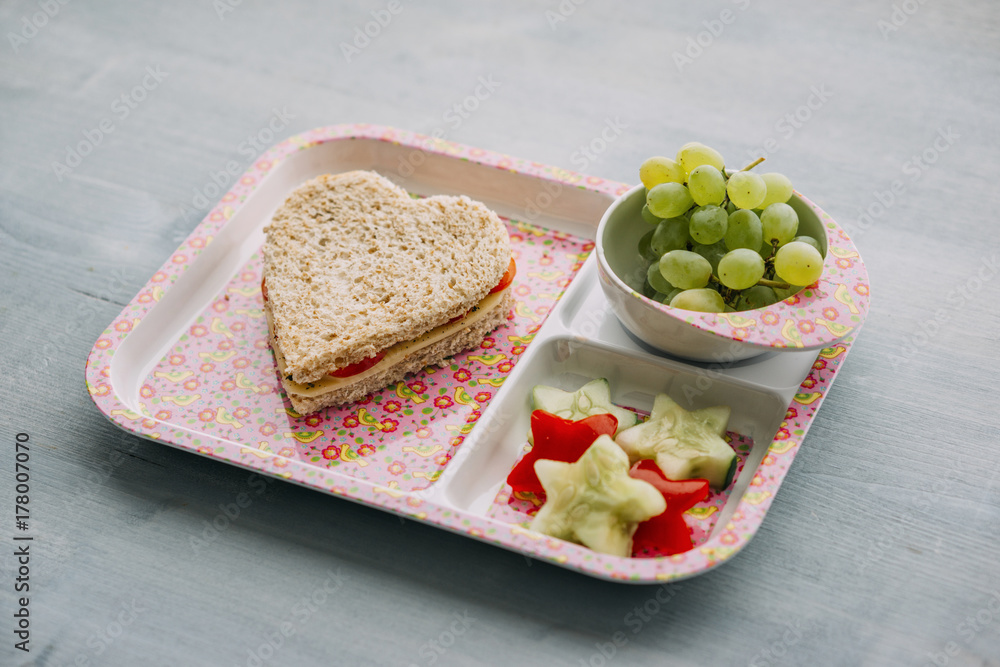 Food: Childrens' school snack, heart-shaped sandwich with cheese and tomato, star-shaped cucumber and bell pepper, grapes Food: Childrens' school snack, heart-shaped sandwich with cheese and tomato, star-shaped cucumber and bell pepper, grapes