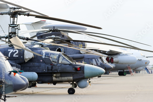 Helicopters and planes in row, military copters and reconnaissance aircrafts, air force, modern army aviation and aerospace industry, dramatic clouds on background photo