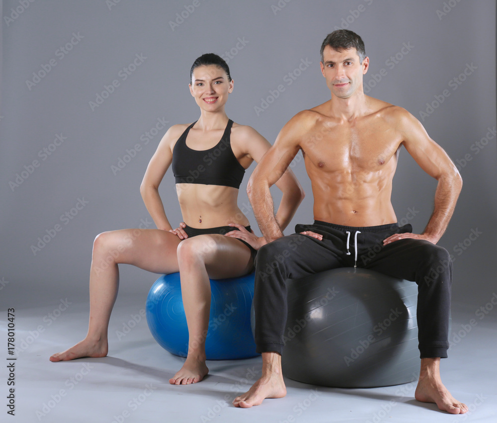 Obraz premium Two smiling people with fitness ball in the gym. Personal fitness instructor. Personal training. Gym workout.