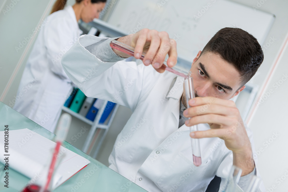 young male scientist holding test tube with blood sample young male scientist holding test tube with blood sample