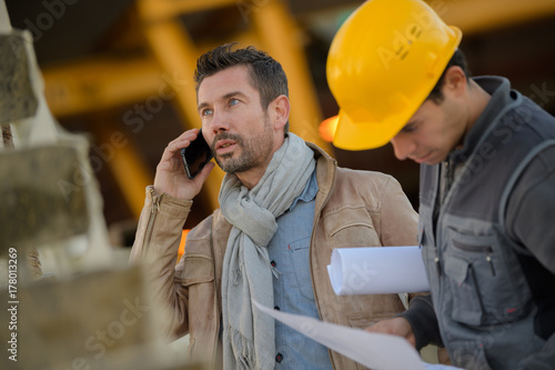 man using phone outside a factory photo