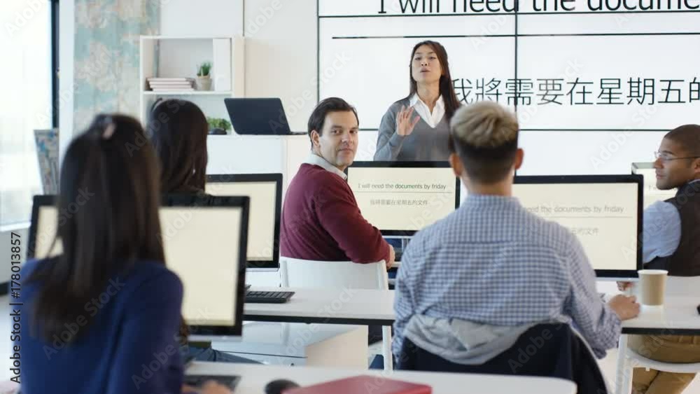 Adult students in language class with video screen showing Asian characters Adult students in language class with video screen showing Asian characters