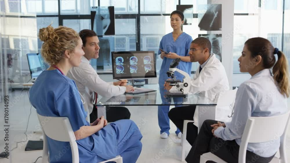 Medical team in a meeting, using technology to look at brain scans & x-rays. Medical team in a meeting, using technology to look at brain scans & x-rays.