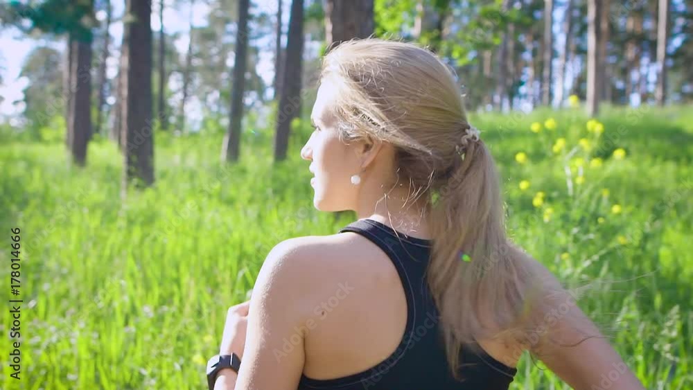 Slow motion shot of a young blonde woman in a sports suit, who actively runs through the park during the day, he enjoys the exercises Slow motion shot of a young blonde woman in a sports suit, who actively runs through the park during the day, he enjoys the exercises