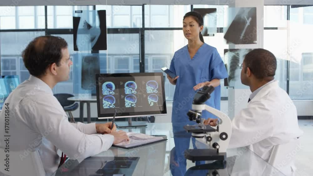 Medical team in a meeting, using technology to look at brain scans & x-rays. Medical team in a meeting, using technology to look at brain scans & x-rays.