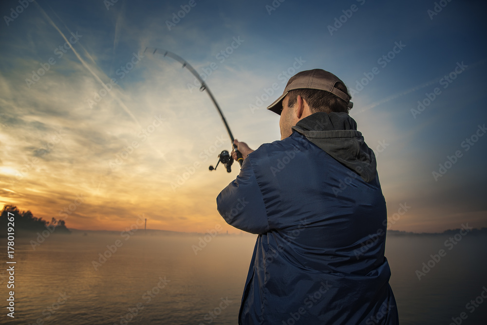 Φωτογραφία Fisherman throwing his rod, fishing from a little boat, beautiful morning sunris
