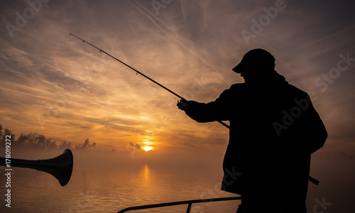 Fisherman throwing his rod, fishing from a little boat, beautiful morning sunrise scene