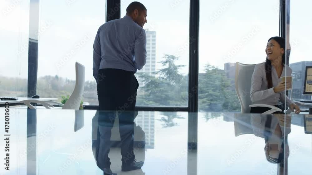 Business man & woman with coffees chatting in front of large office window. Business man & woman with coffees chatting in front of large office window.