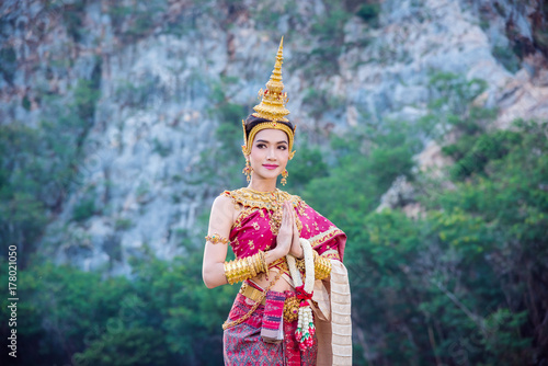 Beautiful asian woman in traditional Thai dress doing gesture welcome and smiles