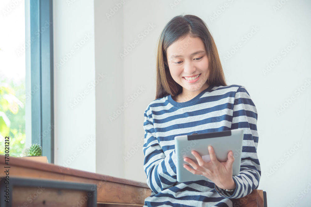 Beautiful young asian woman smiling while using tablet computer at home Beautiful young asian woman smiling while using tablet computer at home